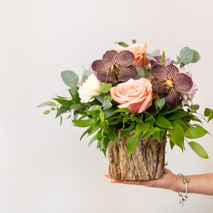 Photo woman holding beautiful flower bouquet in the wooden pot