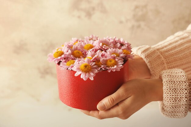 Woman holding beautiful flowers in gift box closeup