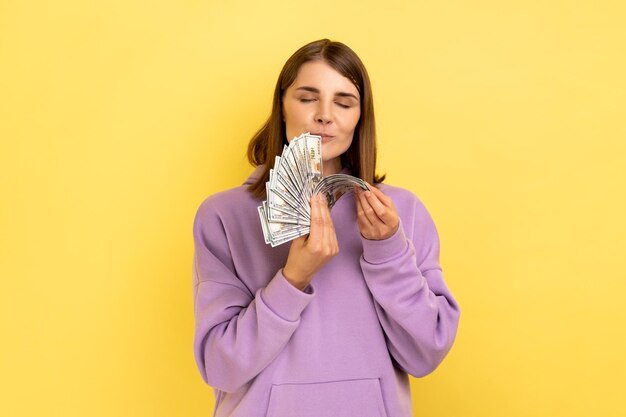 Photo woman holding big fan of money smelling dollar banknotes with pleasure