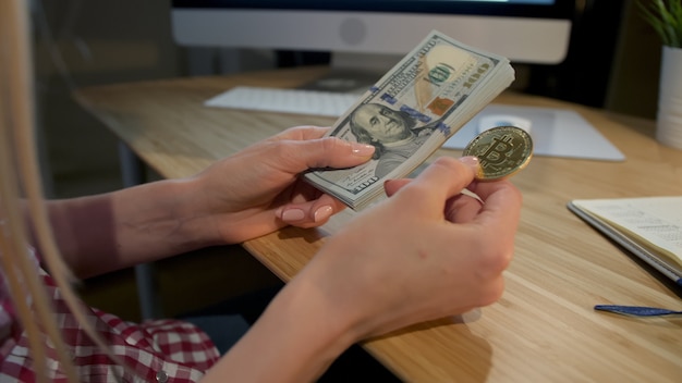 Photo woman holding bitcoin and wad of cash