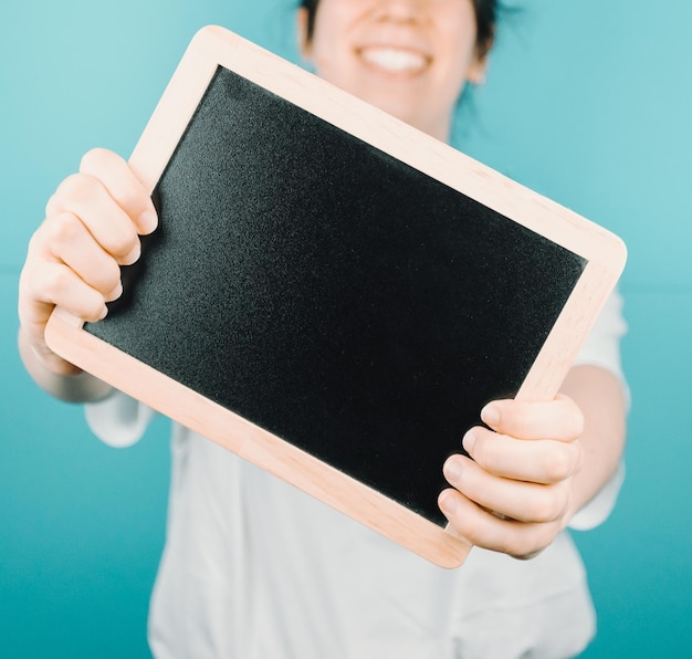 Woman holding a black board with blank space copy space for\
your text to camera while smiling happily mock up scene concept add\
your own text or image color background minimal concept