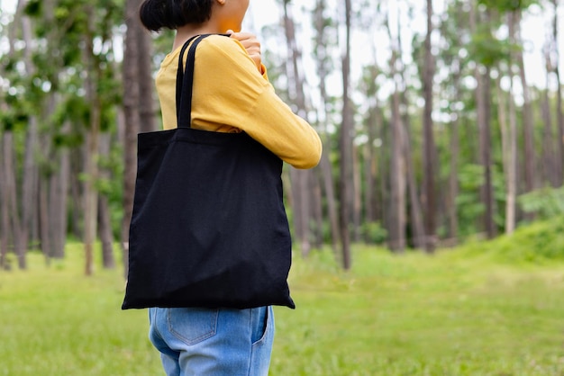 Donna che tiene una borsa di cotone nero sullo sfondo della natura