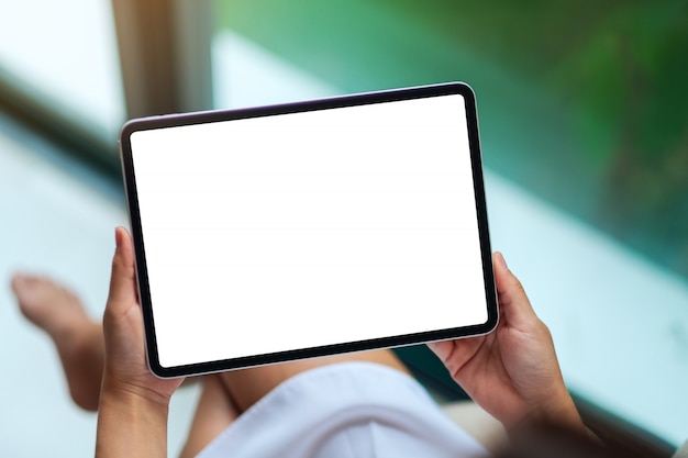  of a woman holding black tablet pc with blank white desktop screen , green nature 