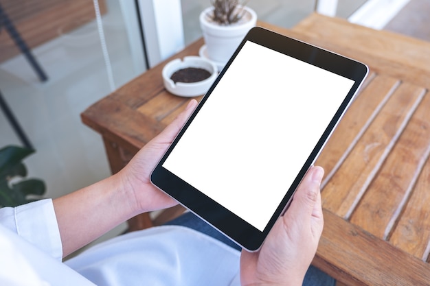 woman holding black tablet pc with blank white screen while sitting