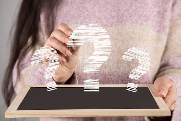 Woman holding blackboard with question mark