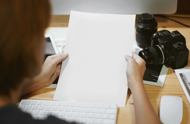 Woman holding blank paper sheet at workplace