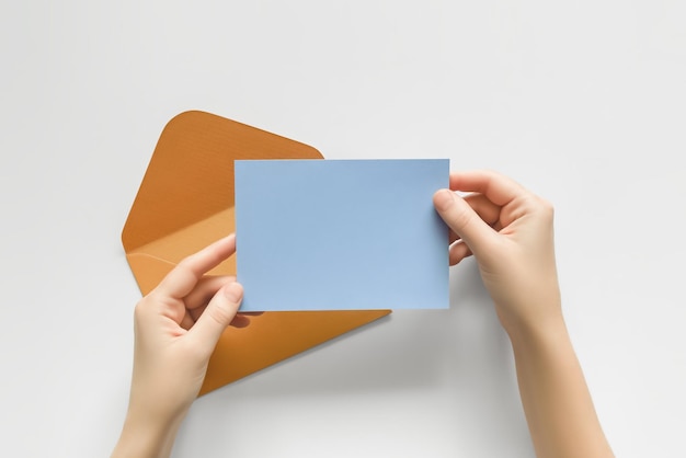 woman holding a blank postcard against the background of an open envelope top view
