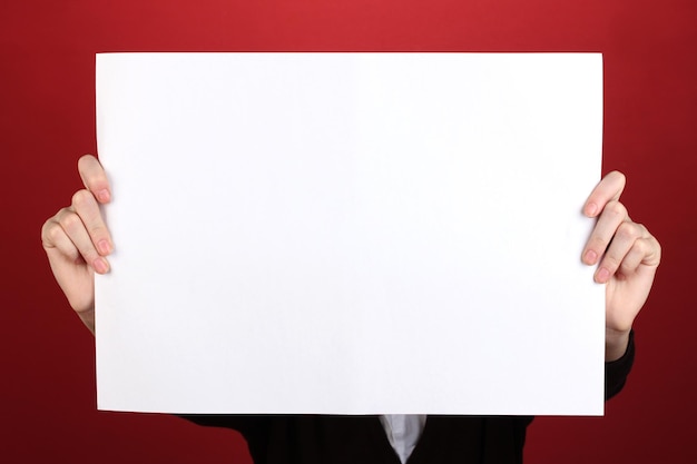 Woman holding blank sign in front her face on color background