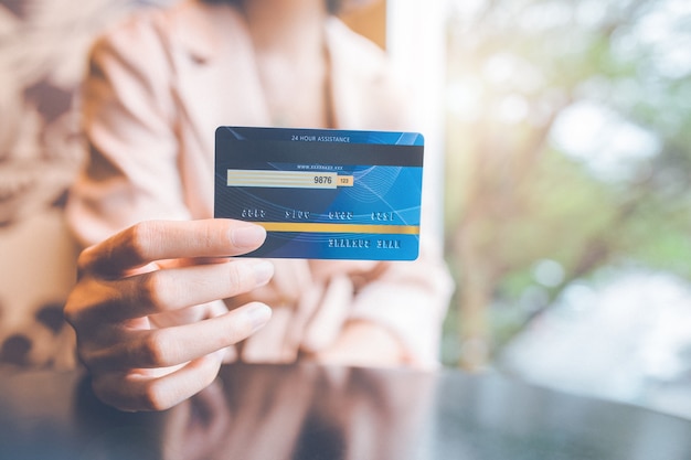 Woman holding a blue credit card to make purchases.