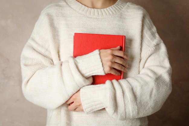 Woman holding book against brown space, front view