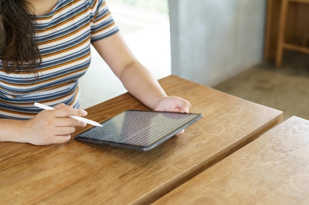 Woman holding a book device reading on ebook on digital tablet device or social media apps online ecommerce