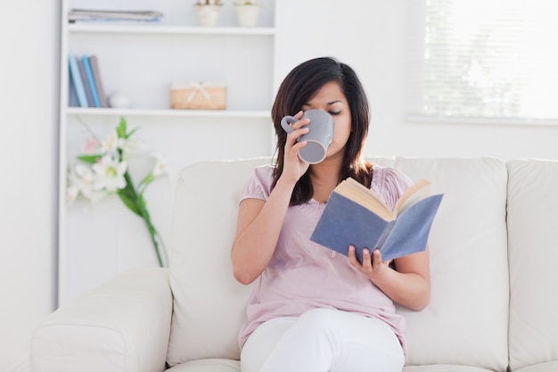 Woman holding a book and drinking