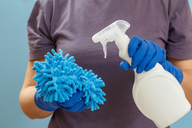 Woman holding a bottle of washing liquid and a rag on a blue background