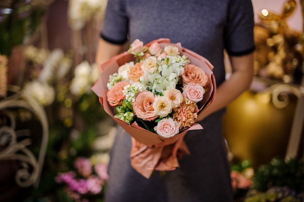 Donna che tiene un mazzo di rose beige e altri fiori