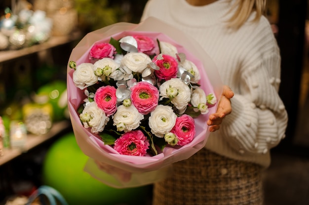 明るいピンクと白の牡丹のバラの花束を持っている女性