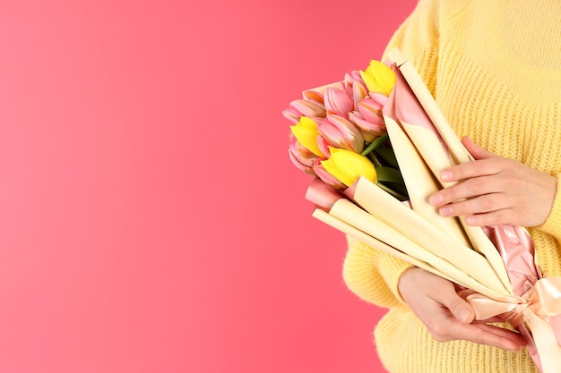 Woman holding bouquet of flowers on pink background