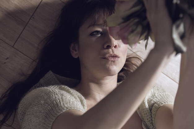 Woman holding bouquet while lying on bed at home