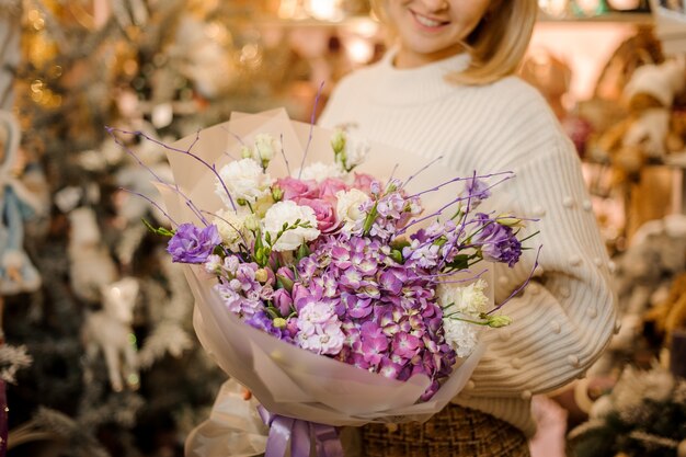 マットな透明な紙に包まれたピンク、紫、白の花の花束を持っている女性