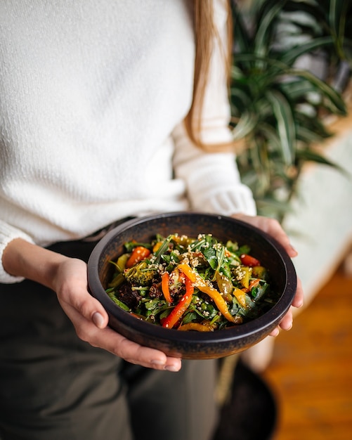 Photo woman holding a bowl of dish with vegetables