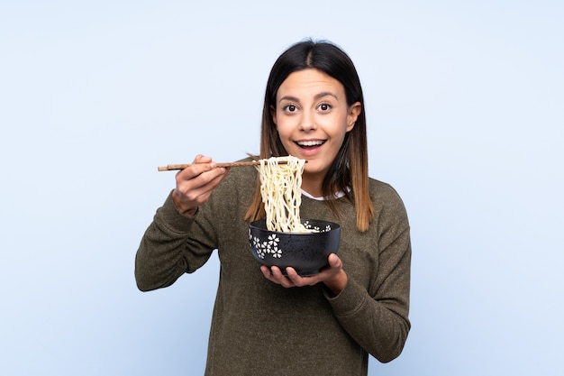 Woman holding a bowl of noodles with chopsticks and eating it