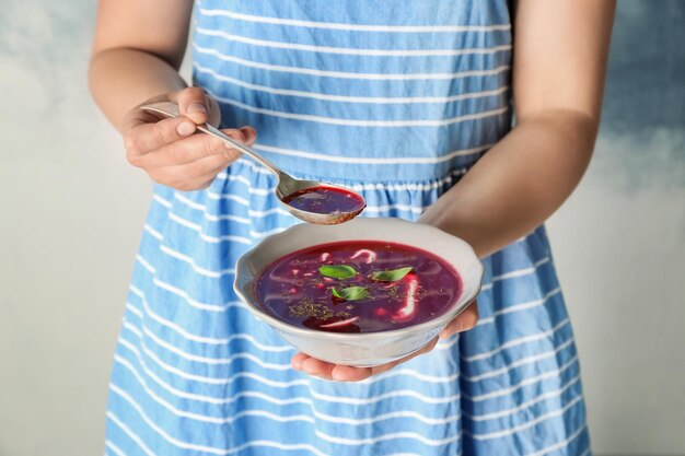 Woman holding bowl and spoon with beet soup closeup