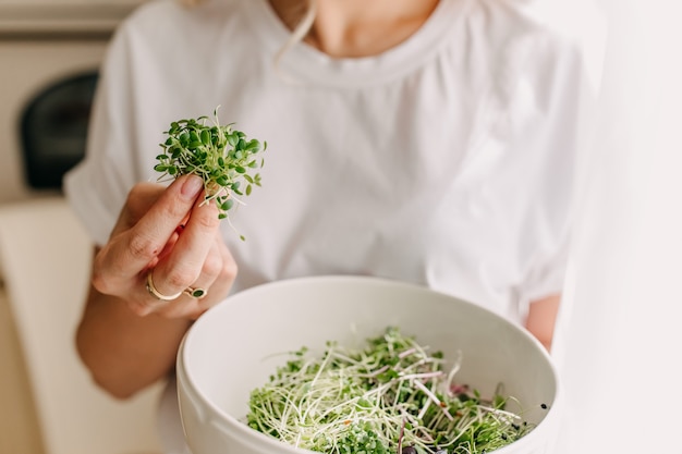 Woman holding a bowl with organic green sprouts