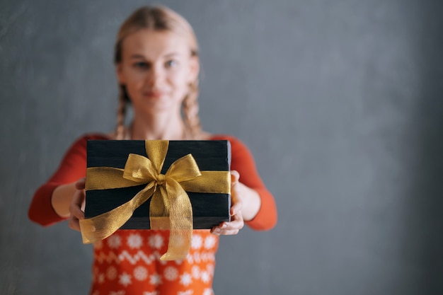 Woman holding a box with a christmas present in her hands in front of her face