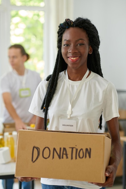 Photo woman holding box with donated products