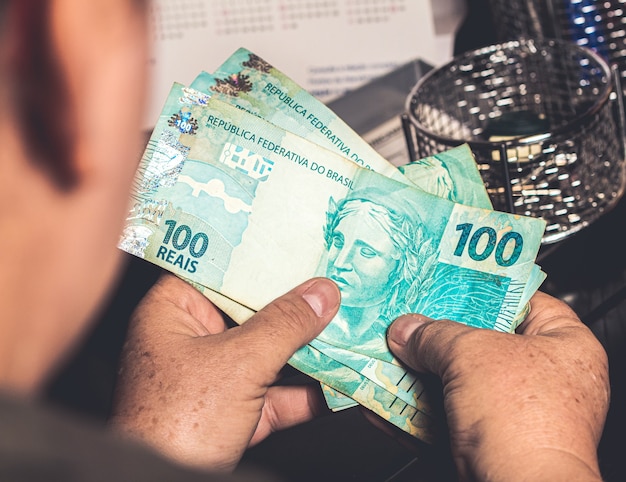 a woman holding a brazilian real banknotes