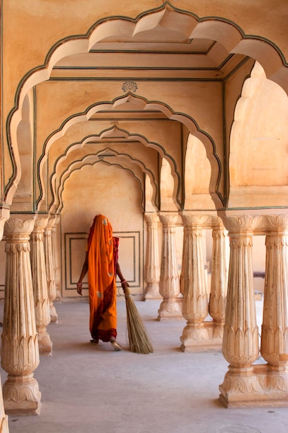 woman holding broom while walking in corridor of historical palace