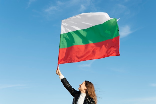 Woman holding bulgarian flag against the blue flag