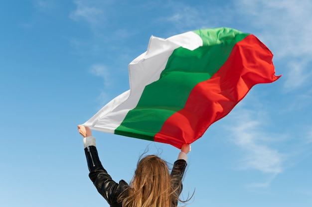 Woman holding bulgarian flag against the blue flag