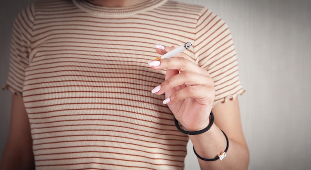 Woman holding burning cigarette. Smoking