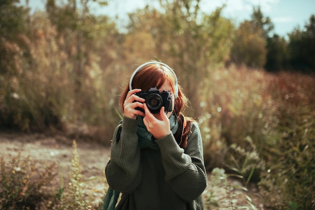 Woman holding camera while standing during winter