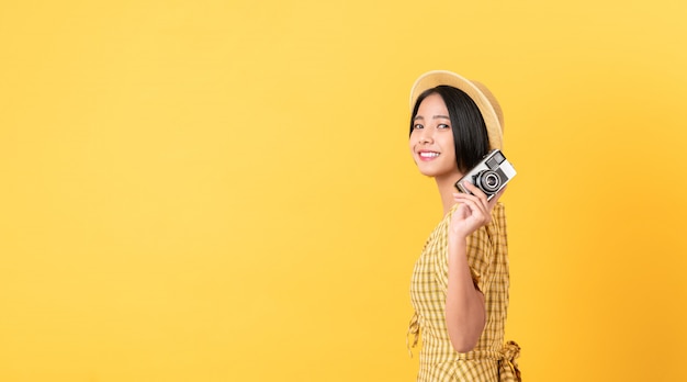 Woman holding camera on yellow background