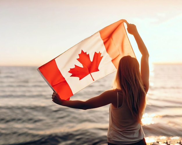a woman holding a canadian flag in front of a body of water.