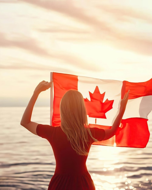 A woman holding a canadian flag in front of a sunset.