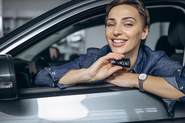 車のキーを押しながら車に座ってスニリングする女性