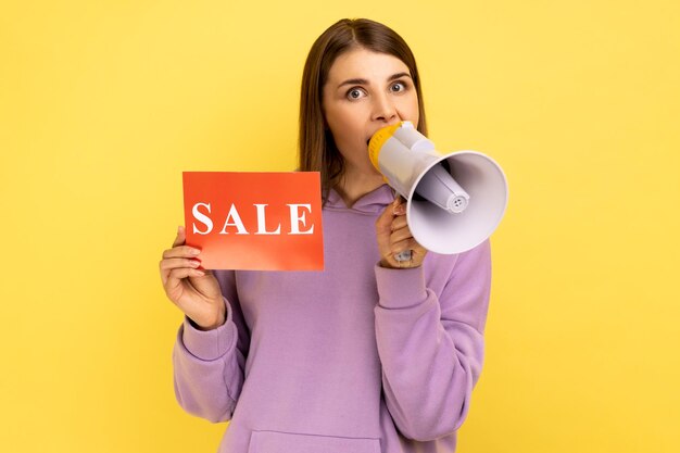 Photo woman holding card with sale inscription and screaming in megaphone about discounts