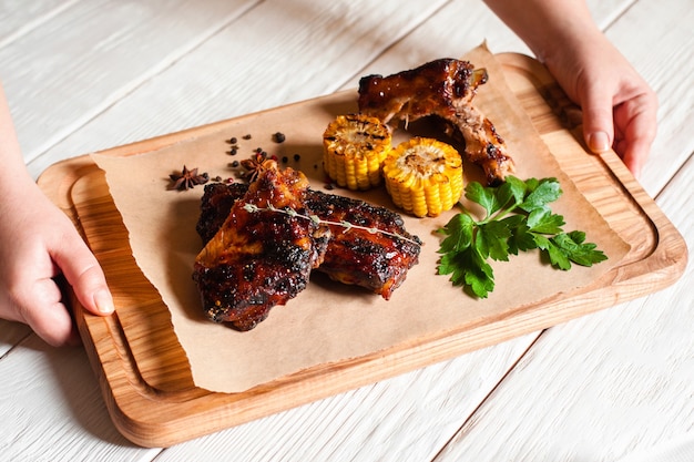 Woman holding catering platter with grilled ribs and corn