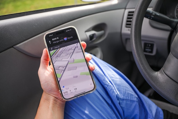 a woman holding a cell phone in her hand while in a car.