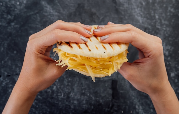 Woman holding a cheese arepa, typical of Venezuelan cuisine.