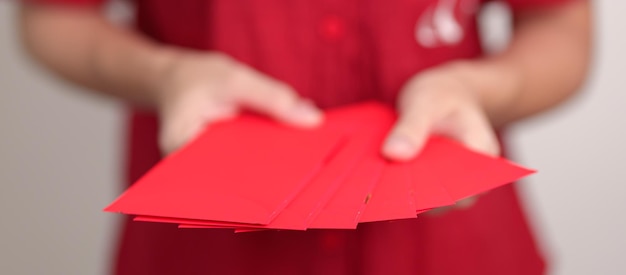 Женщина держит китайский красный конверт с деньгами в подарок на счастливый лунный Новый год