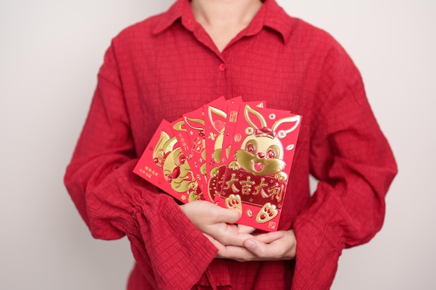 Woman holding Chinese red envelope with golden rabbit and blessing word money gift for happy Lunar New Year holiday Chinese sentence means happiness healthy Lucky and Wealthy