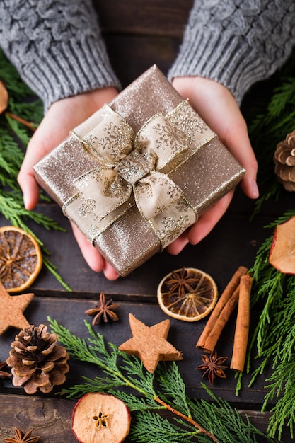 Woman holding Christmas presents laid on a wooden table background.