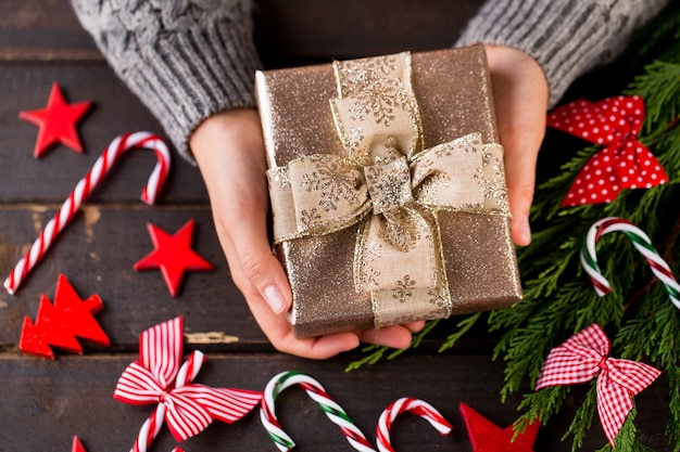 Woman holding Christmas presents laid on a wooden table background.