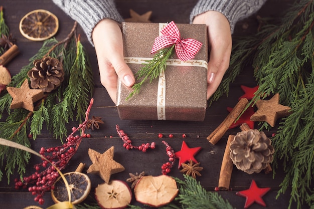 Woman holding Christmas presents laid on a wooden table.