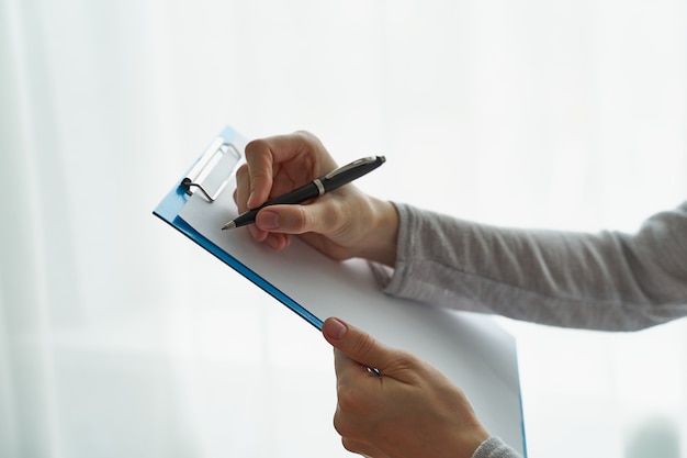 Woman holding clipboard, concept of office work or studying student side view closeup