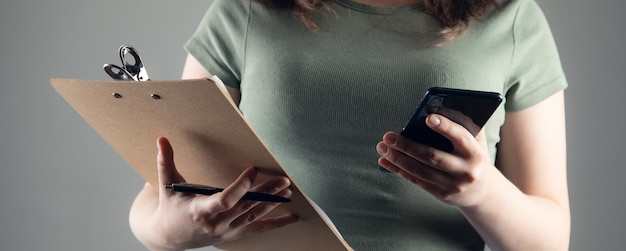 Woman holding clipboard with phone