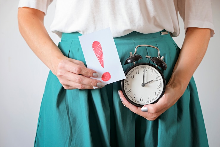 Photo woman holding clock at belly. missed period, unwanted pregnancy and delay in menstruation.